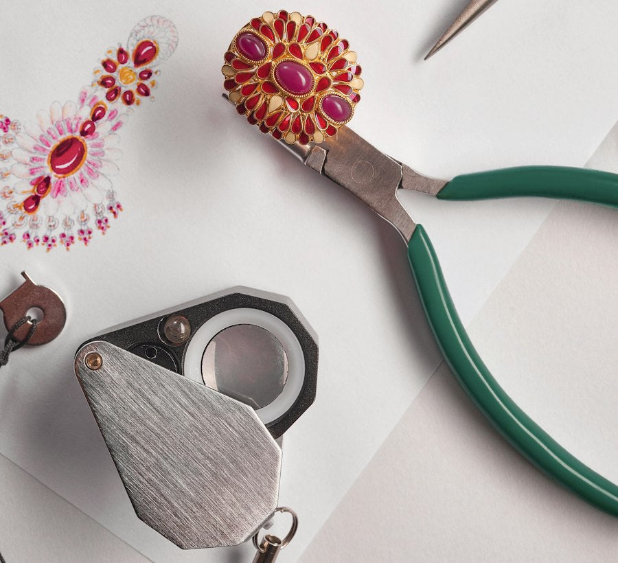 Jewellery design sketches, pliers and a loupe on a bench