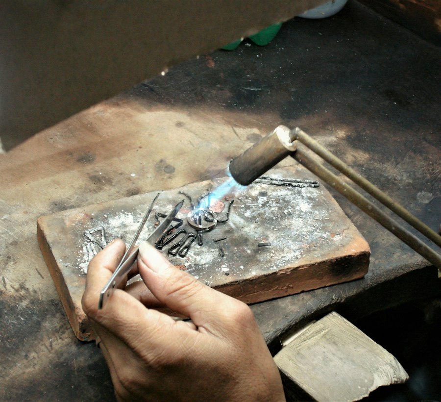 A goldsmith soldering a ring with a torch on a bench block